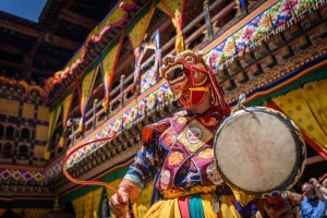 Bután: monje danzando en el festival Paro Tsechu con coloridas máscaras tradicionales