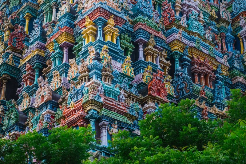 India: coloridos gopurams del templo Meenakshi Sundareswarar entre la vegetación