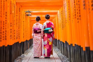 Japón: dos geishas entre los torii rojos del santuario Fushimi Inari en Kioto