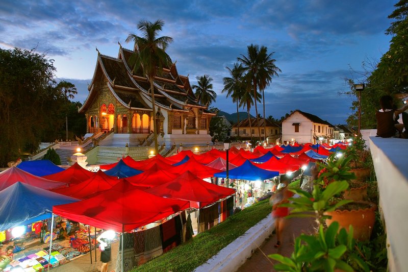 Laos: mercado nocturno de Luang Prabang con tiendas rojas al atardecer