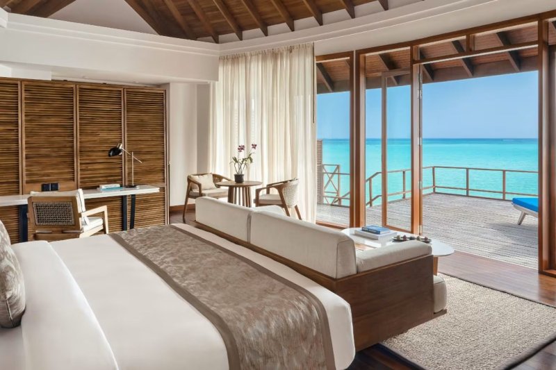 Maldivas: dormitorio de una villa sobre el agua al atardecer en Anantara Dhigu