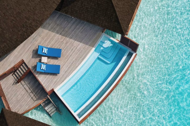 Maldivas: villa sobre el agua con piscina privada al atardecer en Anantara Dhigu