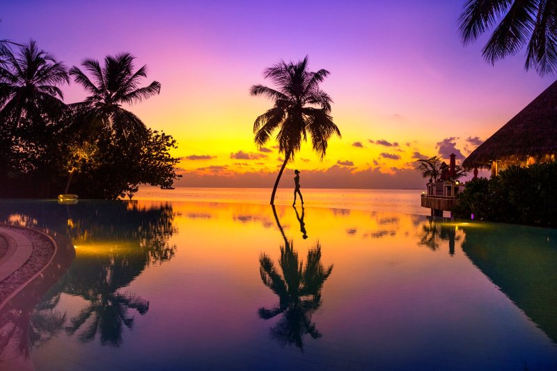 Maldivas: puesta de sol sobre una playa tropical rodeada de palmeras