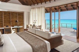Maldivas: dormitorio de una villa sobre el agua al atardecer en Anantara Dhigu