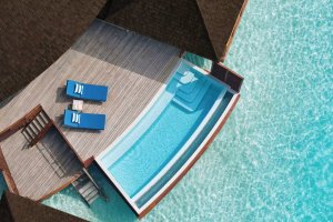 Maldivas: villa sobre el agua con piscina privada al atardecer en Anantara Dhigu