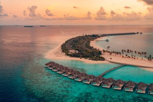 Maldivas: villas sobre el agua al atardecer en un resort de lujo
